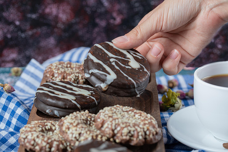 Inicio chocolate and coconut cookies on a wooden board served with a cup of tea