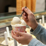 person eating ice cream from cup in shop