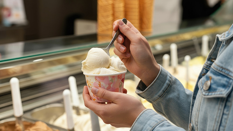 person eating ice cream from cup in shop